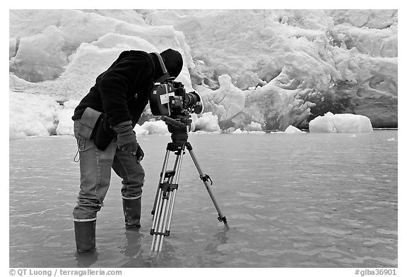 Cameraman standing in water at the base of Reid Glacier. Glacier Bay National Park, Alaska, USA.