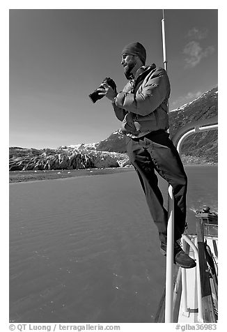 Photographer perched on boat in Reid Inlet. Glacier Bay National Park, Alaska, USA.