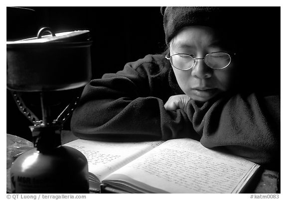 Backpacker reads log in abandonned geological survey cabin, Valley of Ten Thousand smokes. Katmai National Park, Alaska