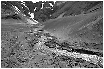 Stream flows from verdant hills into  barren valley floor. Katmai National Park, Alaska, USA. (black and white)