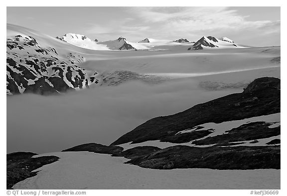 Low clouds, partly melted snow cover, and mountains. Kenai Fjords National Park, Alaska, USA.