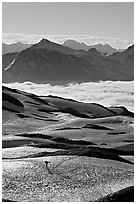 Mountains and sea of clouds, hiker on snow-covered trail. Kenai Fjords National Park, Alaska, USA. (black and white)