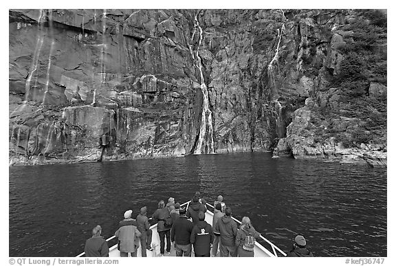 Waterfall viewing from deck of tour boat, Cataract Cove. Kenai Fjords National Park, Alaska, USA.