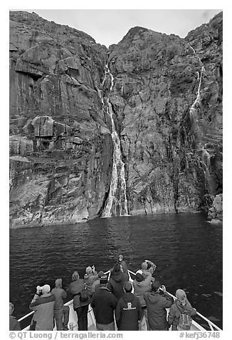Passengers looking at waterfalls from  bow of tour boat, Cataract Cove. Kenai Fjords National Park (black and white)
