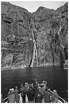 Passengers looking at waterfalls from  bow of tour boat, Cataract Cove. Kenai Fjords National Park, Alaska, USA. (black and white)