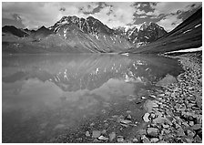 Shore of Turqouise Lake with Telaquana Mountains reflected in silty water. Lake Clark National Park, Alaska, USA. (black and white)