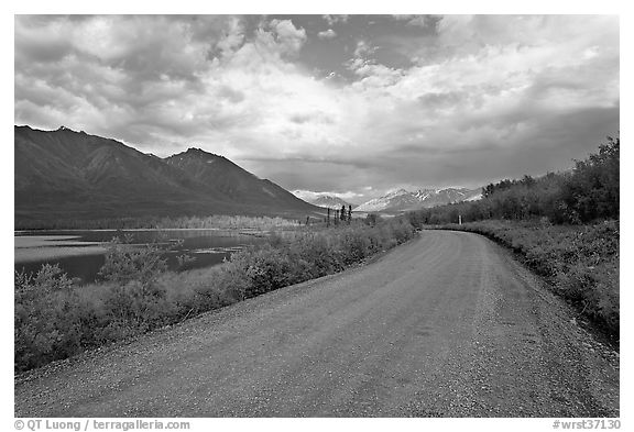 Unpaved McCarthy Road next to lake. Wrangell-St Elias National Park, Alaska, USA.