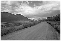 Unpaved McCarthy Road next to lake. Wrangell-St Elias National Park, Alaska, USA. (black and white)