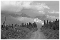 Gravel road leading to mountains lit by sunset light. Wrangell-St Elias National Park, Alaska, USA. (black and white)