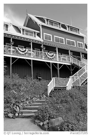 Hiker sitting on steps of Kennicott Lodge. Wrangell-St Elias National Park, Alaska, USA.