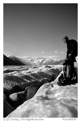 Hiker reaches for item in backpack on Root Glacier. Wrangell-St Elias National Park (black and white)