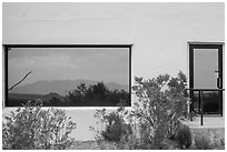 Shrubs, Chisos mountains, Persimmon Gap Visitor Center window reflexion. Big Bend National Park, Texas, USA. (black and white)