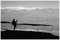 Photographer and Panamint range reflected in a seasonal lake, early morning. Death Valley National Park ( black and white)