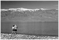 Couple watches the dragon in ephemeral lake. Death Valley National Park, California, USA. (black and white)