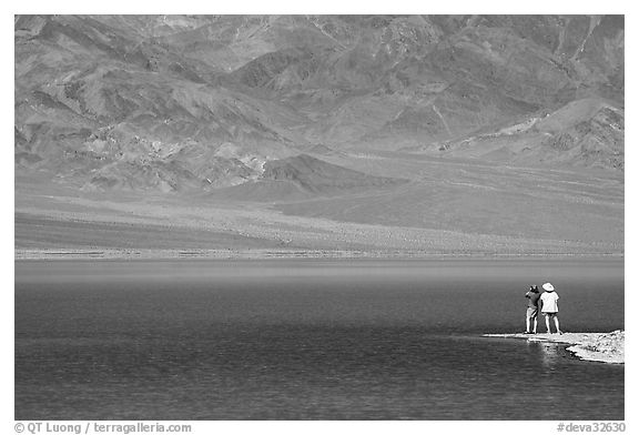 Two tourists on shore of rare lake on the floor of the Valley. Death Valley National Park (black and white)