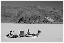 Tourists sunning themselves with beach chairs on the Racetrack. Death Valley National Park, California, USA. (black and white)