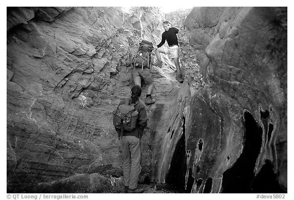 Hikers climbing in a narrow side canyon. Death Valley National Park (black and white)