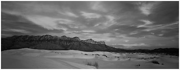White sand dunes, mountain range, and colorful clouds. Guadalupe Mountains National Park (Panoramic black and white)