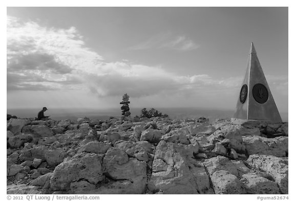 Hiker sitting on Guadalupe Peak summit with cairn and monument. Guadalupe Mountains National Park (black and white)
