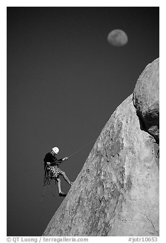 Climber rappelling down with moon. Joshua Tree National Park, California, USA.