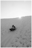 Woman sledding down dune. White Sands National Park ( black and white)