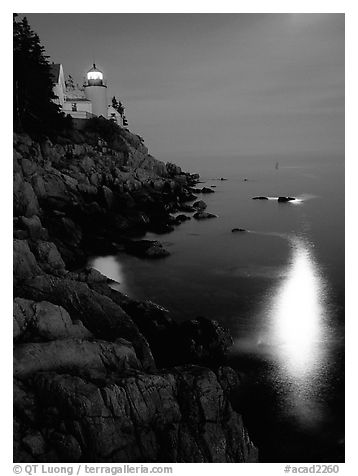 Bass Harbor lighthouse by night with reflections of moon and lighthouse light. Acadia National Park, Maine, USA.