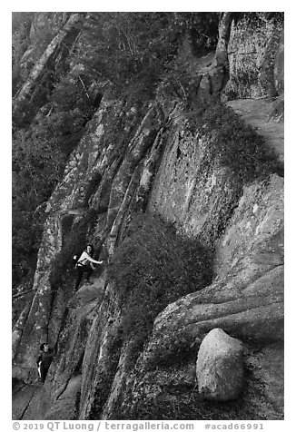 Hikers scaling cliff with iron rungs. Acadia National Park (black and white)