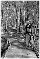 Hiker with backpack standing on boardwalk. Congaree National Park, South Carolina, USA. (black and white)