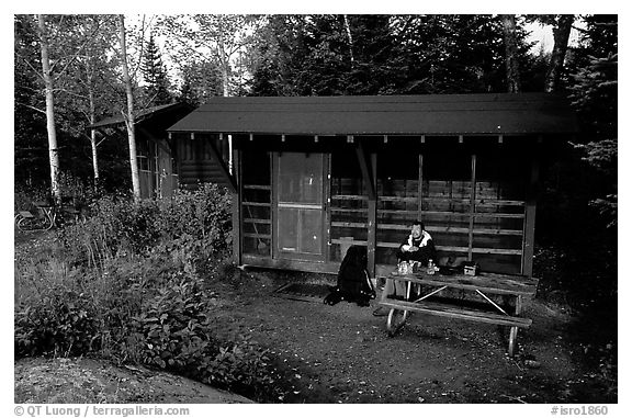 Backpacker sitting in shelter at Chippewa harbor. Isle Royale National Park, Michigan, USA.