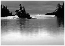 Islet and bright sky reflected in water below dark clouds. Isle Royale National Park ( black and white)