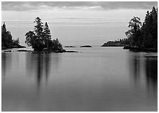 Tree-covered islet and smooth waters, Chippewa Harbor. Isle Royale National Park, Michigan, USA. (black and white)