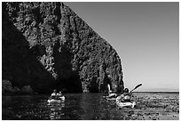 Kayakers paddling in kelp at base of sea cliff, Santa Cruz Island. Channel Islands National Park ( black and white)