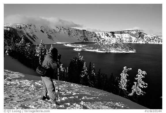 Photographer on  rim of  Lake in winter. Crater Lake National Park, Oregon, USA.