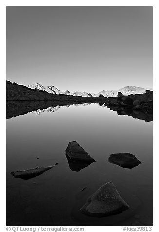 Rocks and calm lake with mountain reflections, early morning, Dusy Basin. Kings Canyon National Park, California, USA.