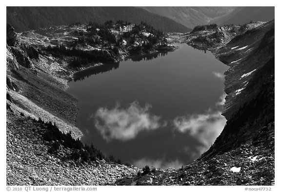 Fluffy clouds reflected in blue lake, North Cascades National Park.  (black and white)