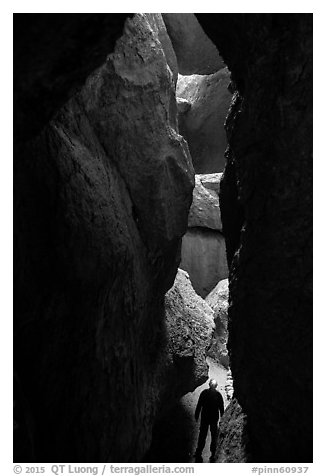 Hiker in narrow and deep section of Lower Bear Gulch Cave. Pinnacles National Park (black and white)