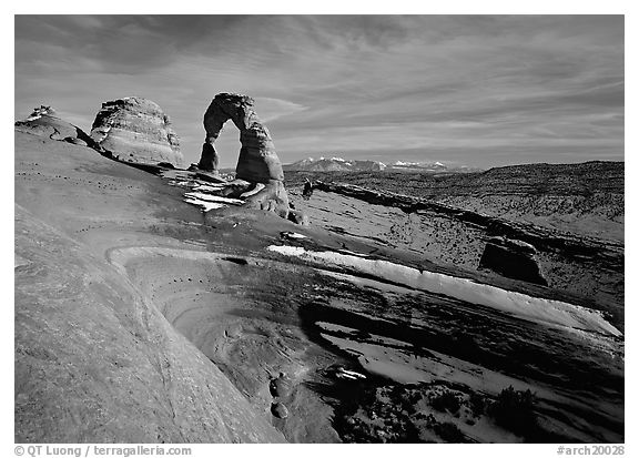 Sandstone bowl, Delicate Arch, and La Sal Mountains with snow, sunset. Arches National Park, Utah, USA.