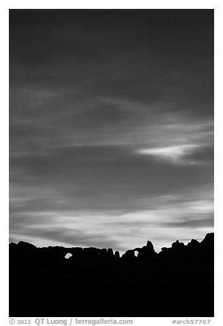 Windows and Turret Arch silhouetted against colorful clouds. Arches National Park (black and white)