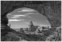 Park visitor looking, Turret Arch framed by North Window. Arches National Park, Utah, USA. (black and white)