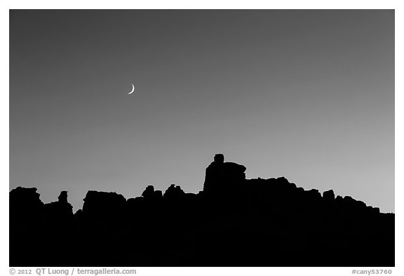 Crescent moon at sunset and Doll House spires. Canyonlands National Park, Utah, USA.