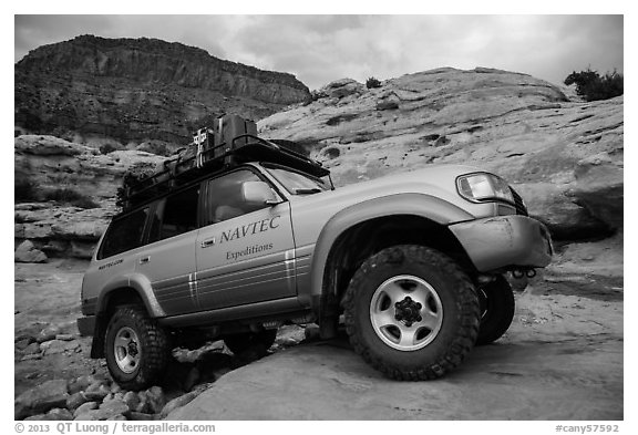 Expedition vehicle driving over rock ledge, Teapot Canyon. Canyonlands National Park, Utah, USA.