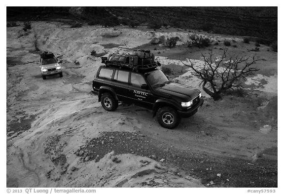 4WD vehicles driving over rock at dusk in Teapot Canyon. Canyonlands National Park, Utah, USA.