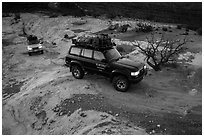 4WD vehicles driving over rock at dusk in Teapot Canyon. Canyonlands National Park, Utah, USA. (black and white)