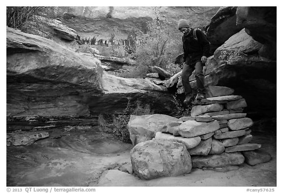 Hiker stepping down on primitive stairs, Maze District. Canyonlands National Park, Utah, USA.