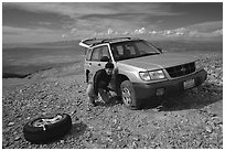 Man changing a flat tire on remote spot at top of Mt Washington. Great Basin National Park, Nevada, USA. (black and white)
