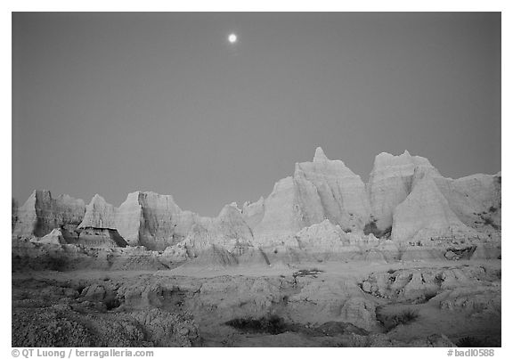 Moon and eroded badlands, Cedar Pass, dawn. Badlands National Park, South Dakota, USA.