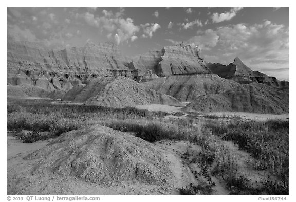 Grasses, cracked soil, and sharp peaks at dawn. Badlands National Park, South Dakota, USA.