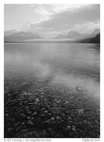 Pebbles, lake Mc Donald, and foggy mountain range, early morning. Glacier National Park, Montana, USA.