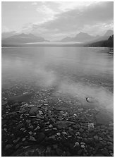 Pebbles, lake Mc Donald, and foggy mountain range, early morning. Glacier National Park, Montana, USA. (black and white)