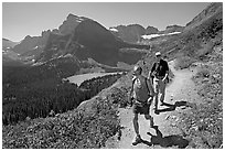 Couple hiking on trail, with Grinnell Lake below. Glacier National Park, Montana, USA. (black and white)